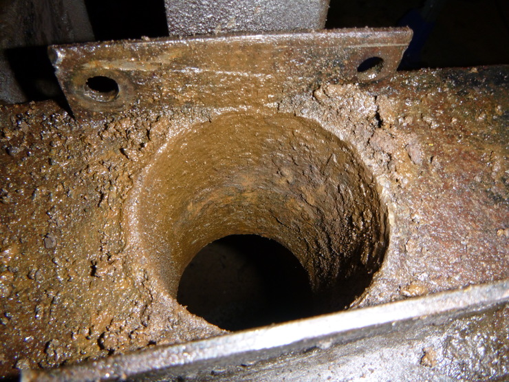 Rusty, gummed-up hole through chassis crossmember